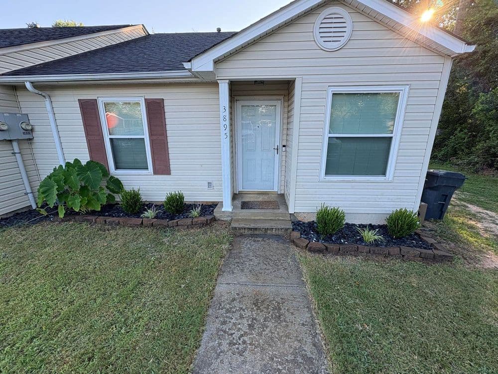 Front entrance of a charming single-story house with landscaped garden and clear pathway.