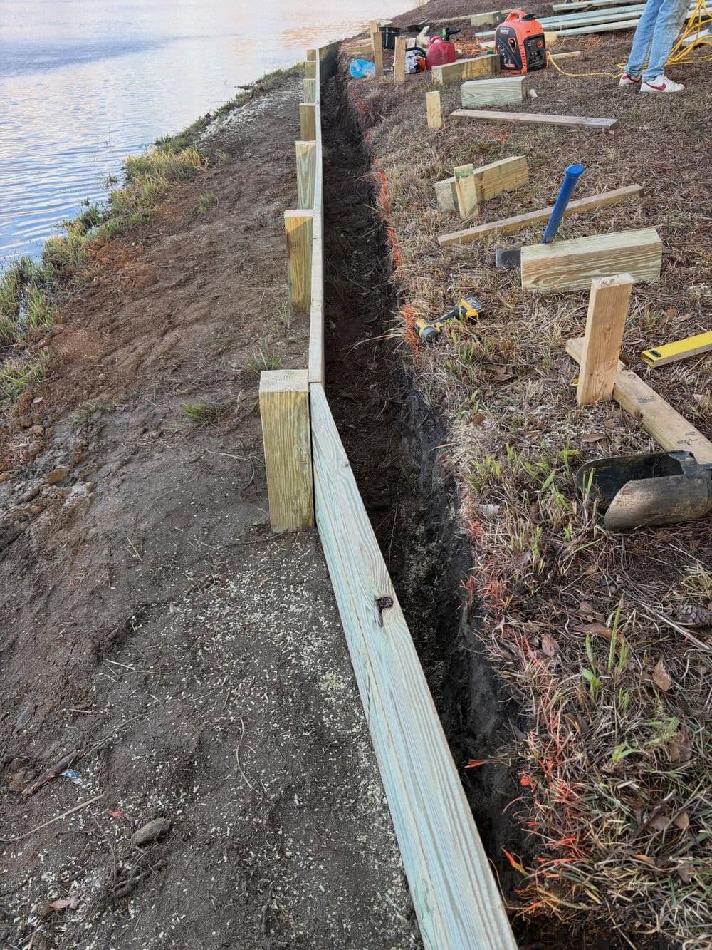 Construction project showing a wooden frame being built along a waterfront, with tools nearby.